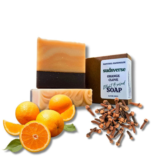 Handmade soap bars with oranges, cloves, and packaging on a white background