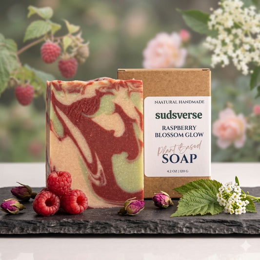 Handmade soap bar with raspberry and green swirls next to its packaging on a natural background with raspberries and flowers.