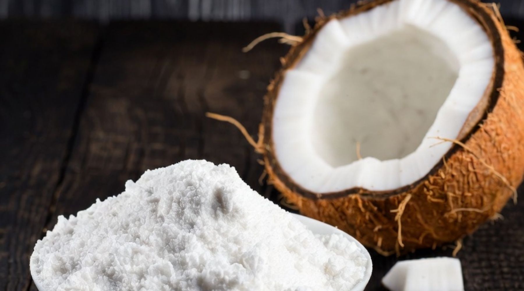 Coconut and sodium cocoyl isethionate powder on a dark wooden surface