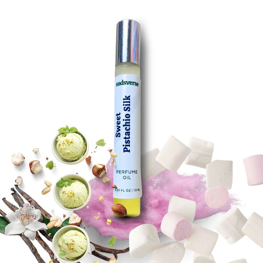 Perfume oil bottle labeled 'Sweet Pistachio Silk' surrounded by pistachios, flowers, and marshmallows on a white background.